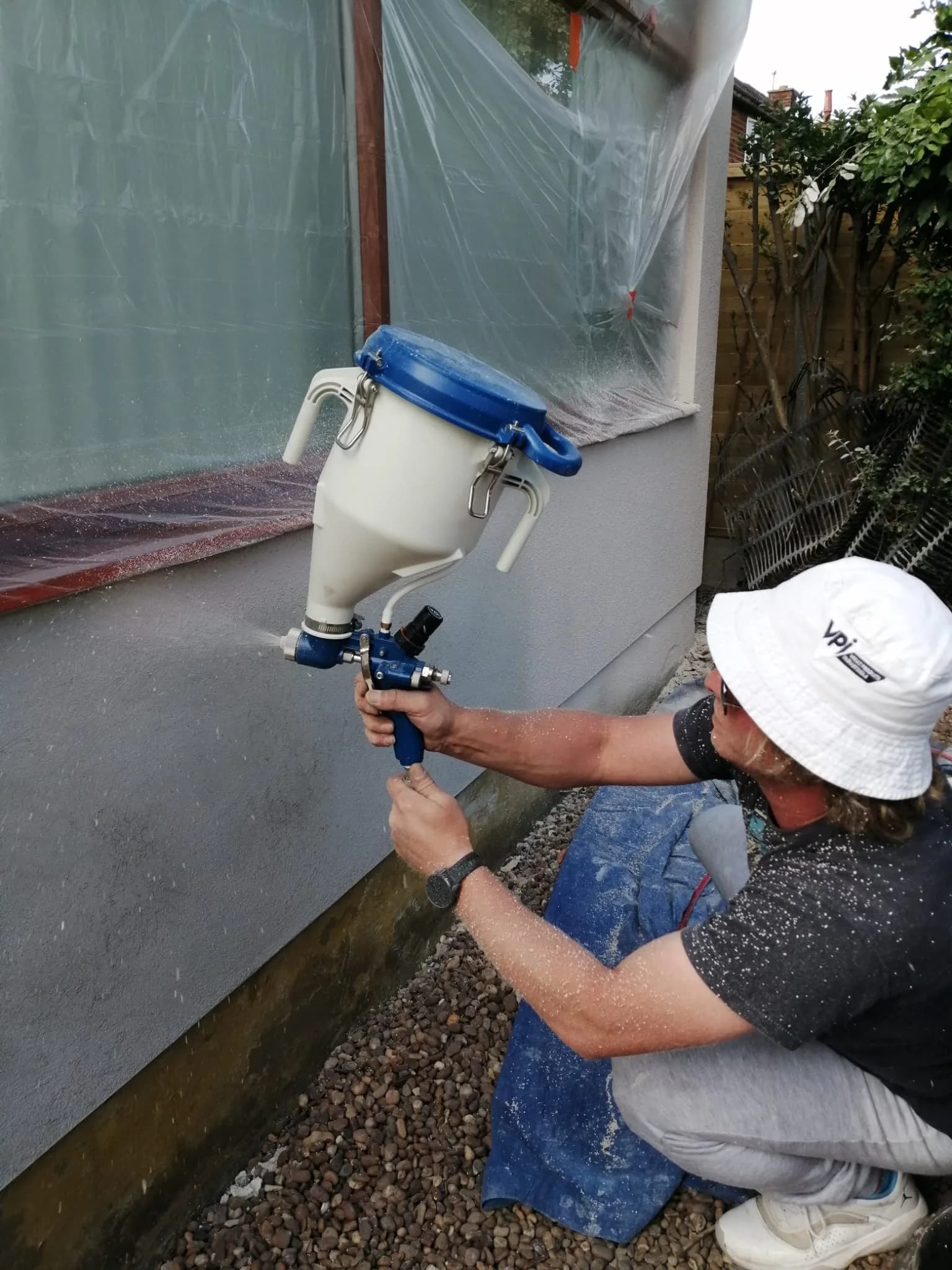 Silicone render being applied by spray gun to EWI system